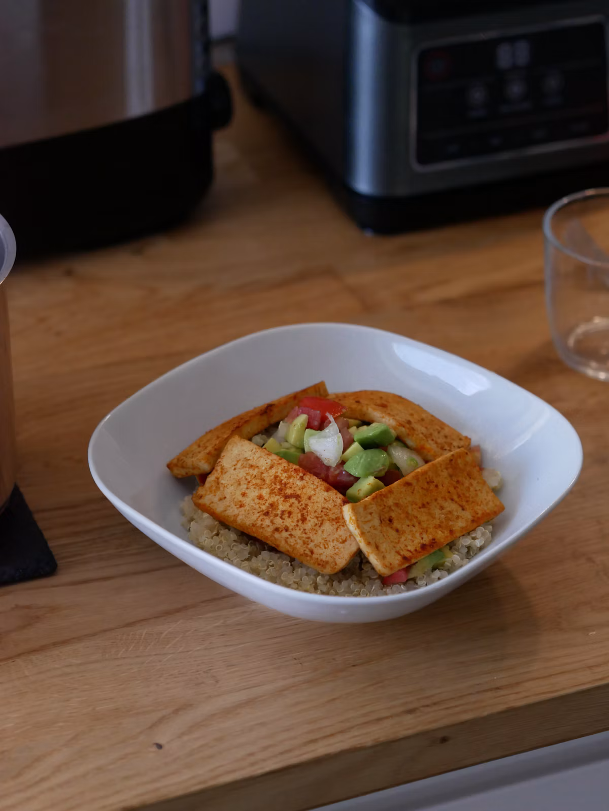 A grain bowl with quinoa, tofu, avocado, and roasted vegetables arranged for a balanced plate